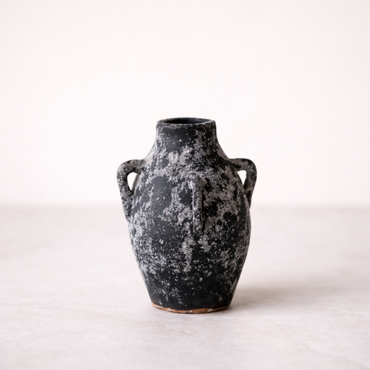 Black ceramic vase with textured surface on a light background