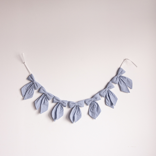 Blue mini gingham fabric bow garland by Luxe B Co, featuring small blue and white checkered fabric bows for decoration.