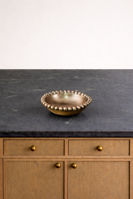 Bronze bowl on a dark countertop with wooden cabinets in the background