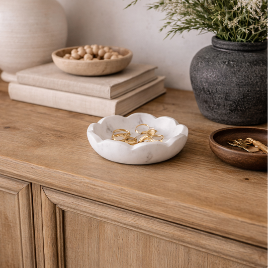 Wooden sideboard with decorative items including a lamp, books, and a vase with flowers.