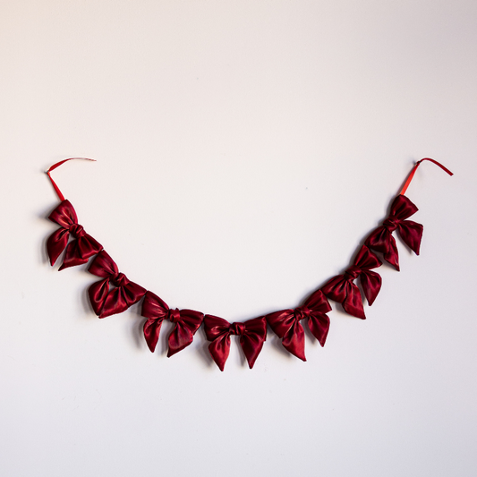 Red gauze bow garland featuring multiple soft fabric bows, ideal for party or event decoration by Luxe B Co.