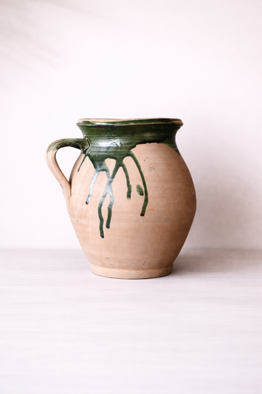 Ceramic pitcher with green accents on a white background
