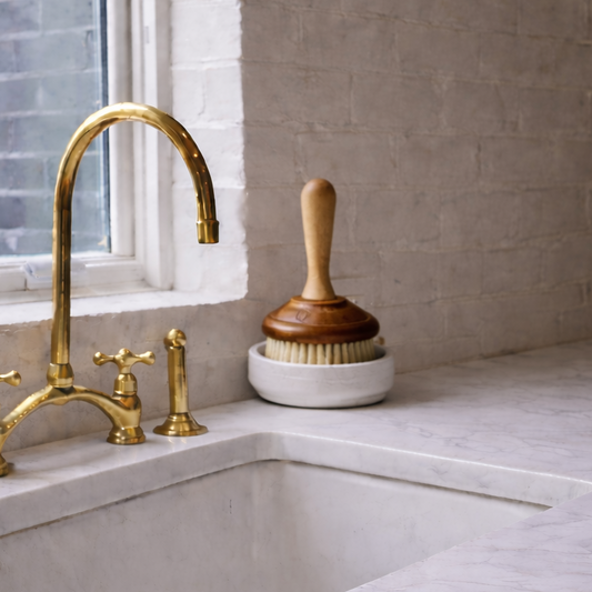 Kitchen sink with gold faucet and window in background