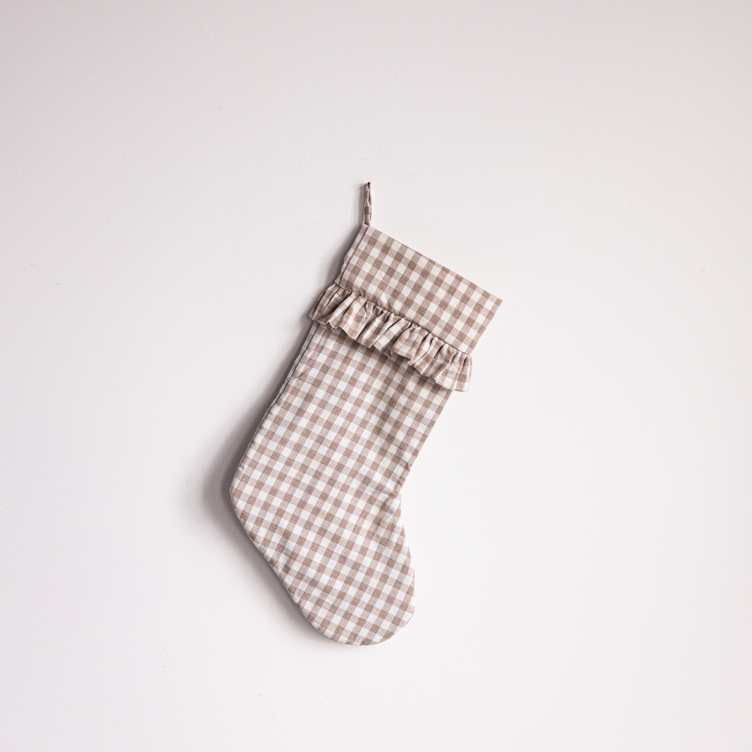 Beige gingham holiday stocking by Luxe B Co with festive pattern and plush cuff for seasonal decor.