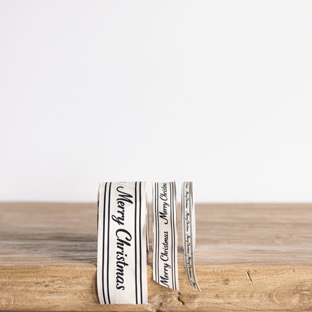 Black cursive Christmas ribbon with "Merry Christmas" text from Luxe B Co Wholesale, ideal for holiday gift wrapping and decorations.