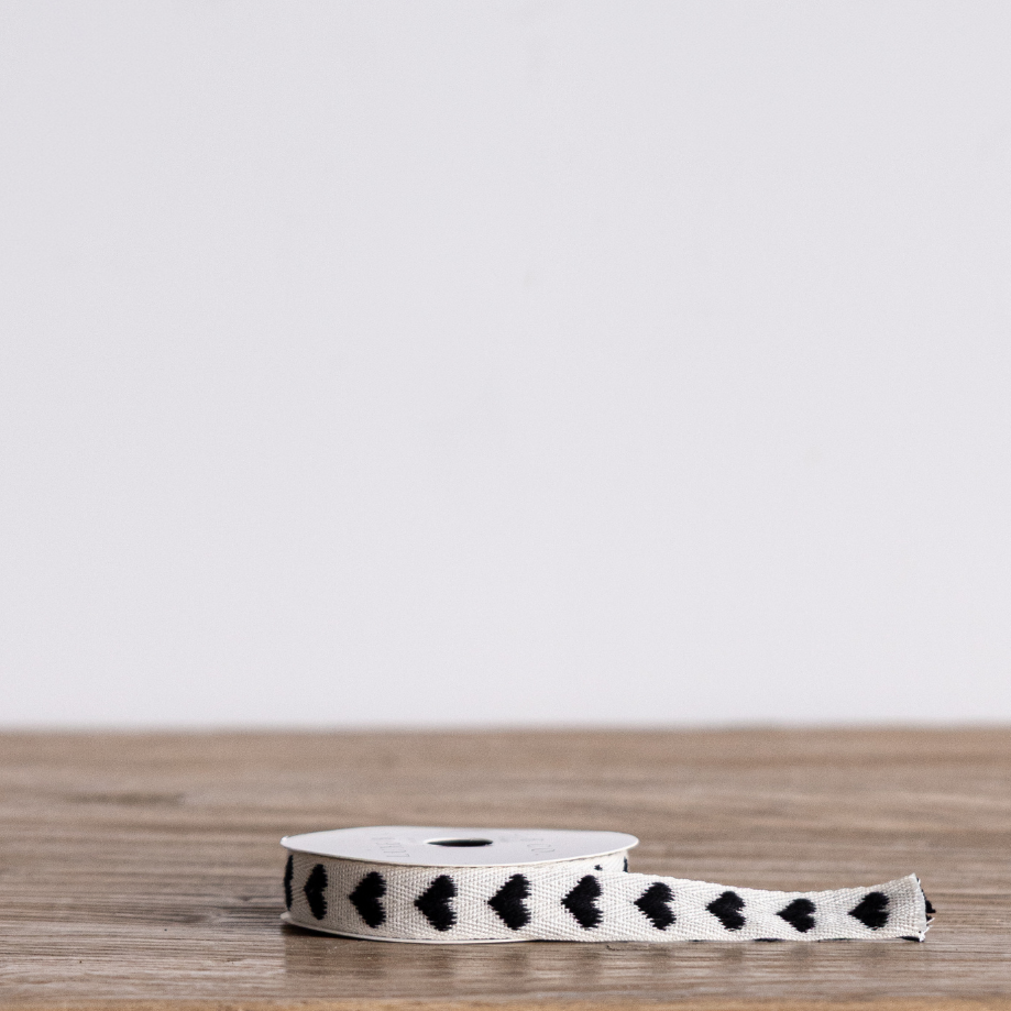 Black woven ribbon with heart patterns from Luxe B Co, ideal for gift wrapping or craft projects.