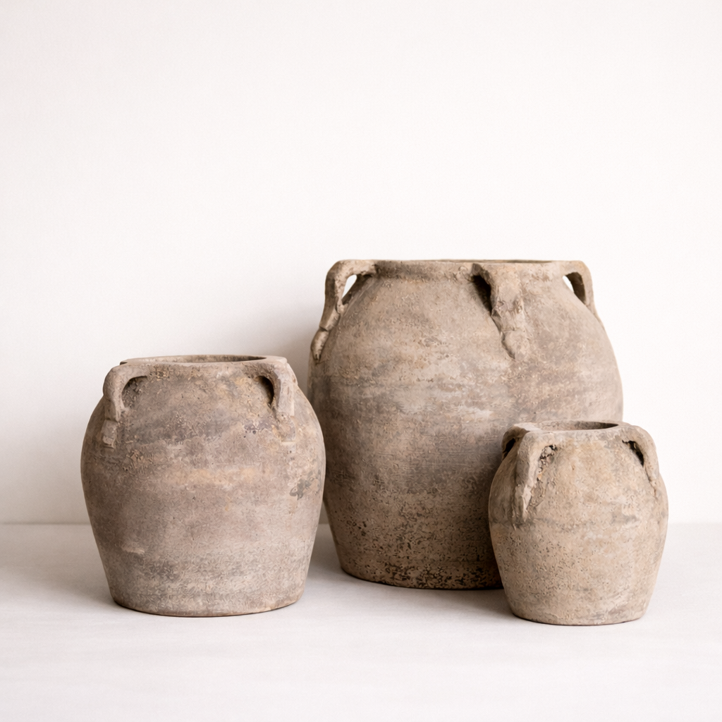 Three rustic clay pots of varying sizes on a white background