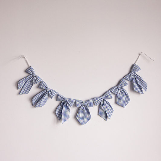 Blue small gingham fabric bow garland by Luxe B Co, featuring multiple tied bows on a string for decorative use.