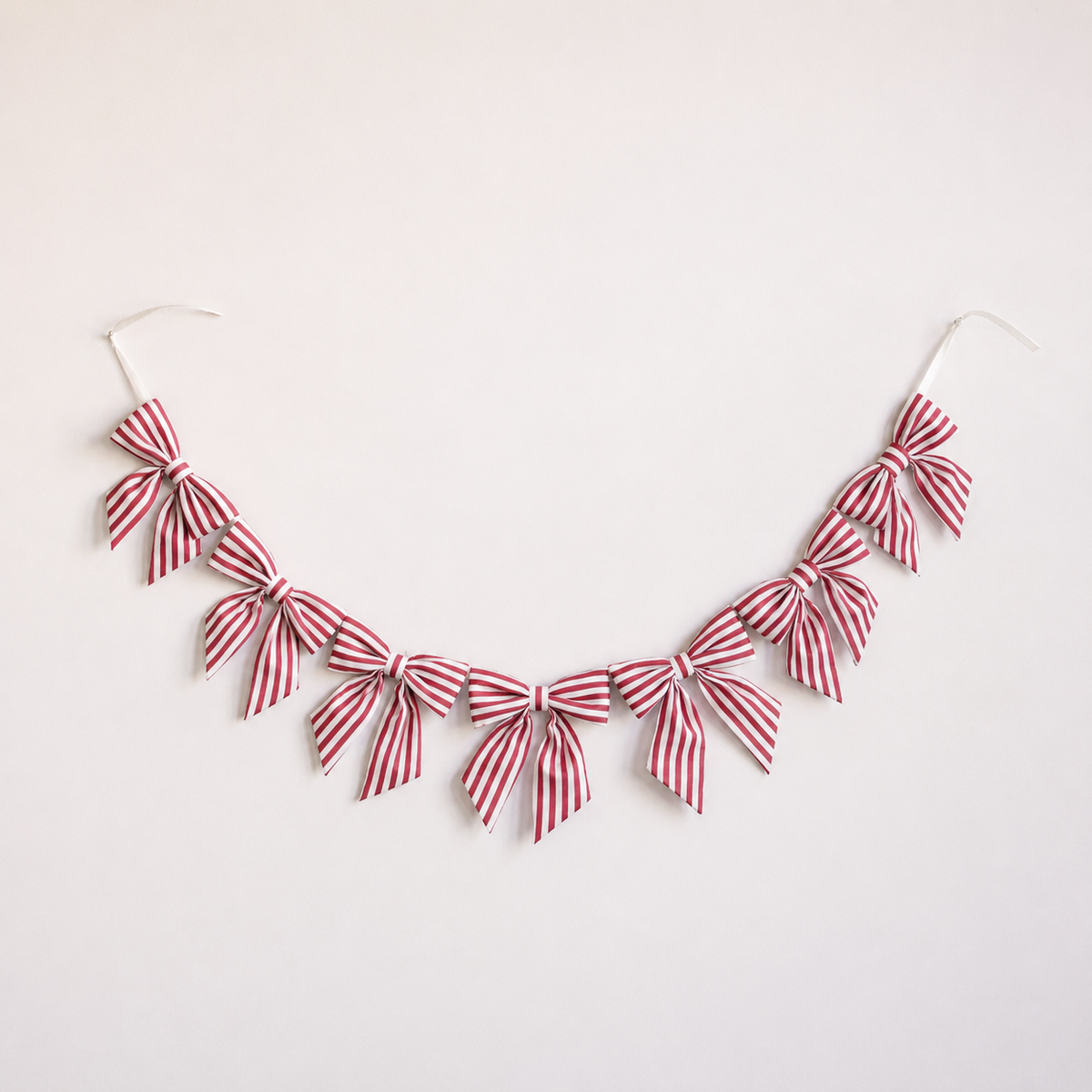 Red fabric bow garland with candy cane accents from Luxe B Co, perfect for festive holiday decorations and celebrations.