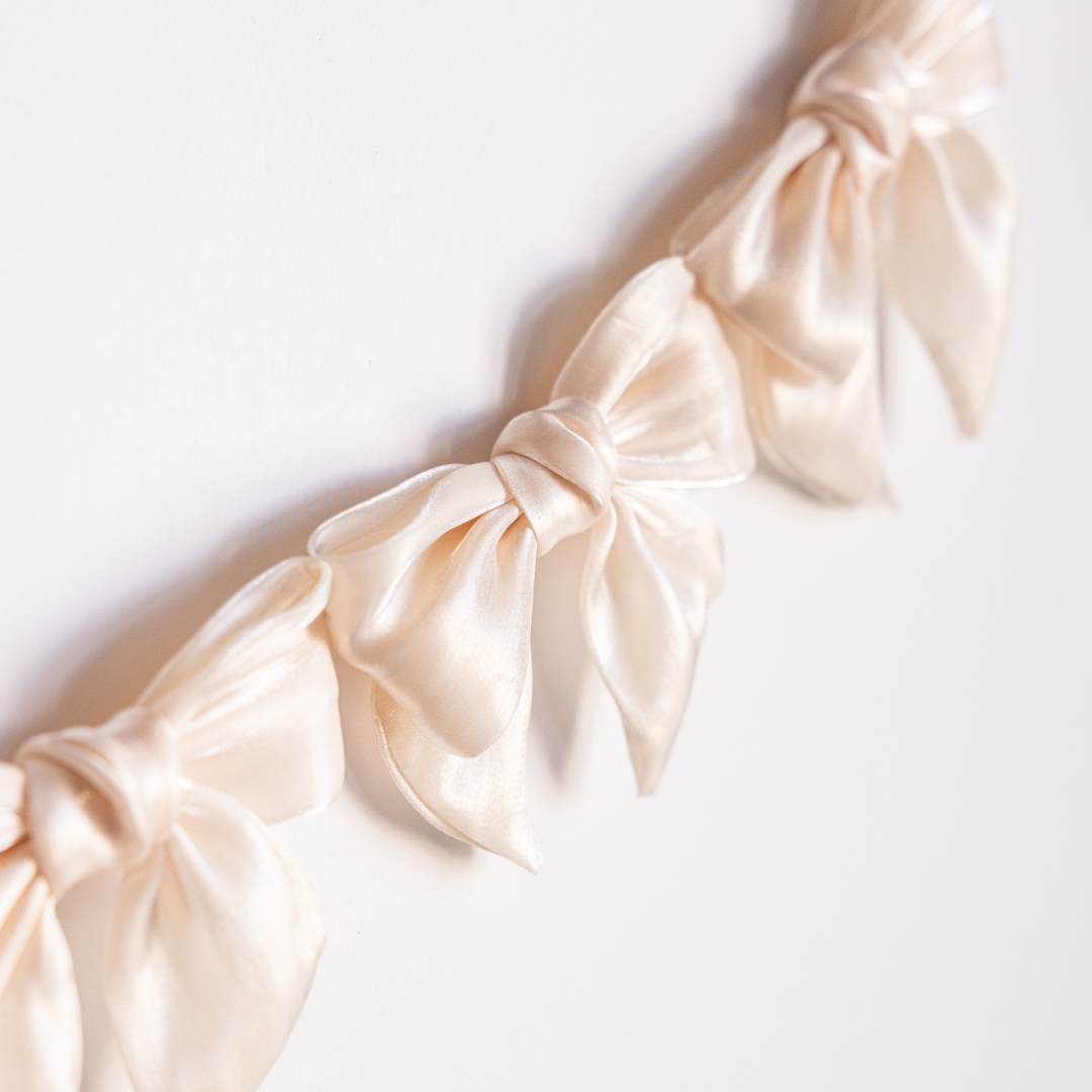 Cream gauze bow garland by Luxe B Co featuring soft, airy fabric bows for elegant party or event decoration.