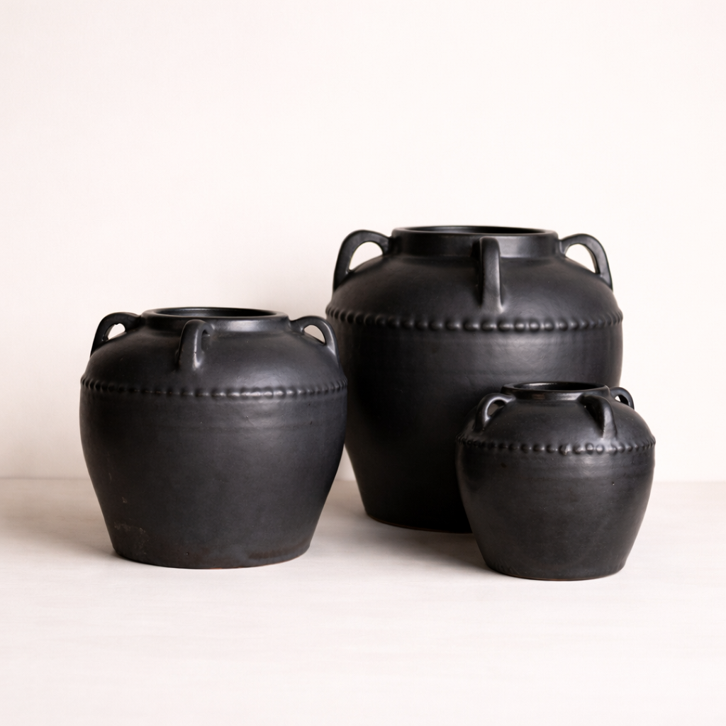 Three black leather-bound containers on a white background