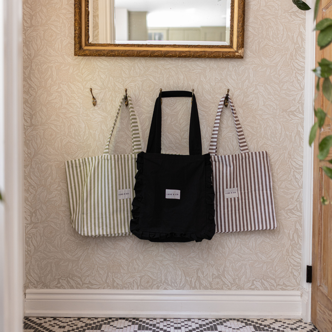 Black Luxe B Co. tote bag with stylish ruffle detailing, spacious design, and sturdy handles for everyday use.