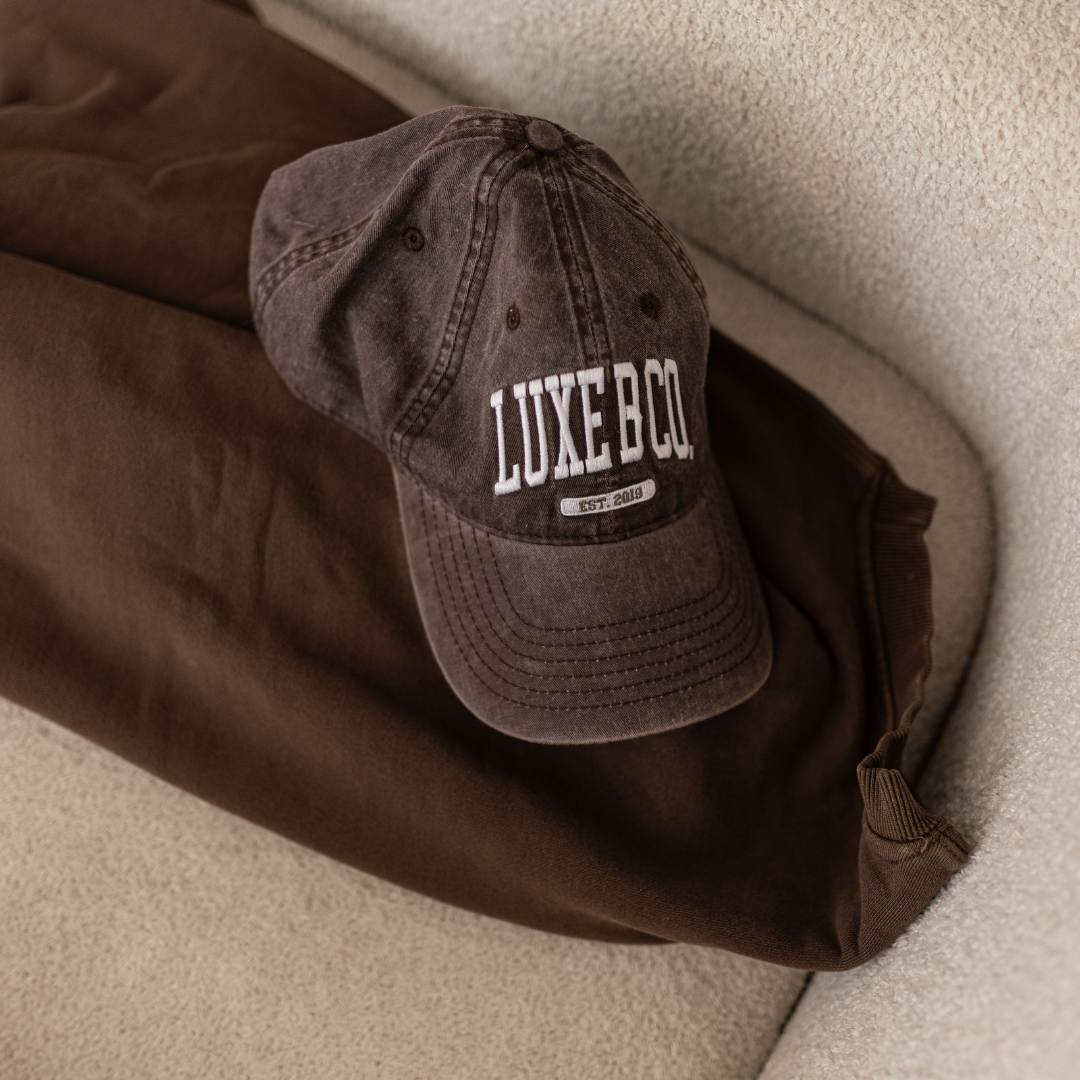 Brown baseball cap by Luxe B Co featuring a classic design and adjustable strap, perfect for casual wear.