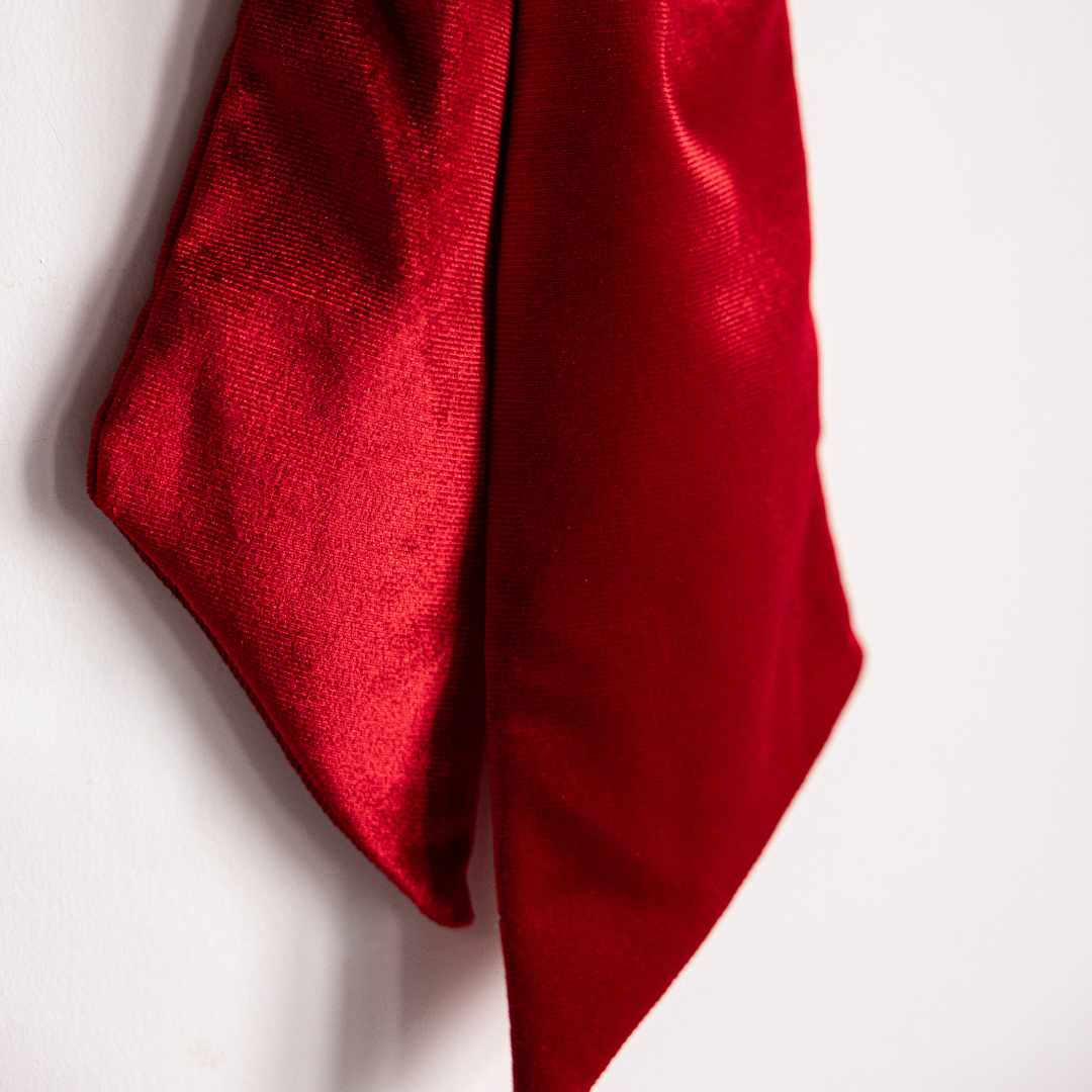Red velvet fabric bow by Luxe B Co, shown in close-up detail, highlighting soft texture and elegant design.