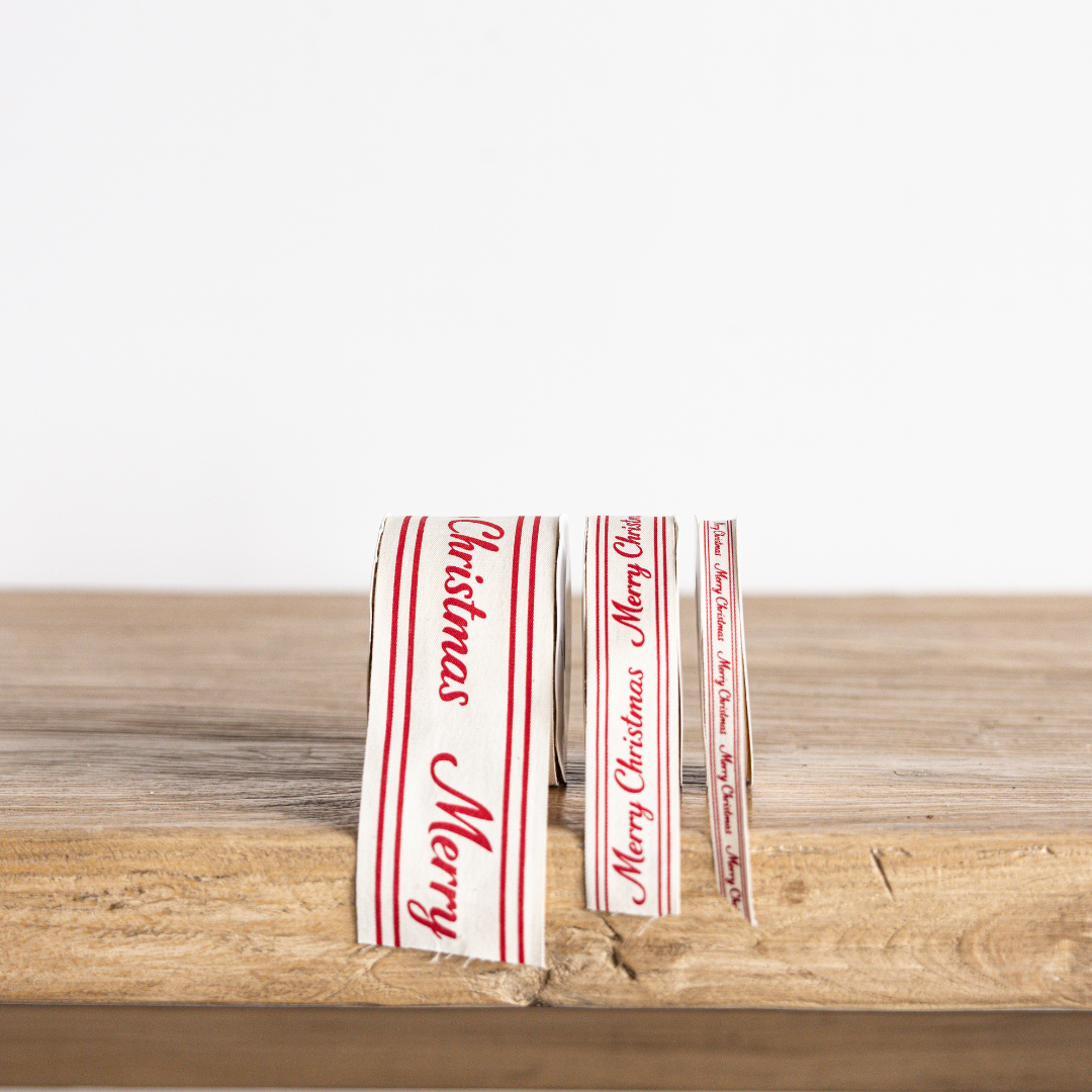 Red cursive "Merry Christmas" ribbon by Luxe B Co Wholesale, showing festive holiday decoration with elegant script design.