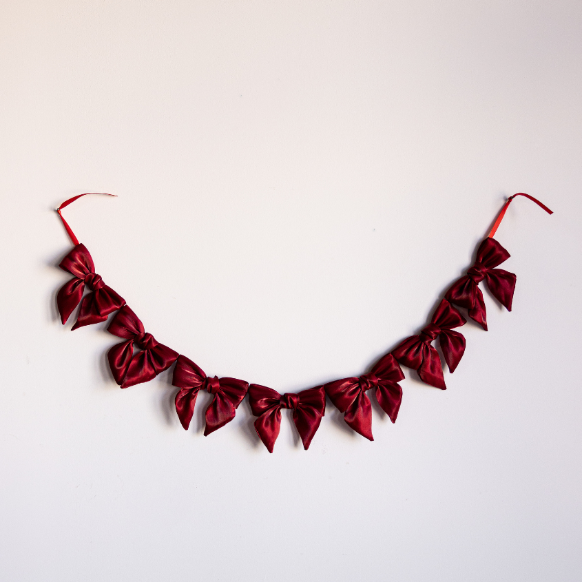 Red gauze bow garland featuring multiple soft fabric bows, ideal for party or event decoration by Luxe B Co.