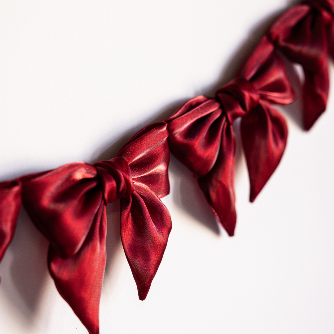 Red gauze bow garland with multiple fabric bows, decorative and suitable for festive or party decor by Luxe B Co.