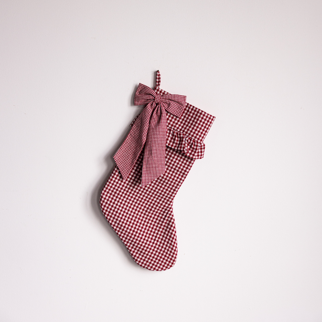 Red gingham holiday stocking with a bow from Luxe B Co, featuring festive red and white checkered fabric and decorative bow detail.