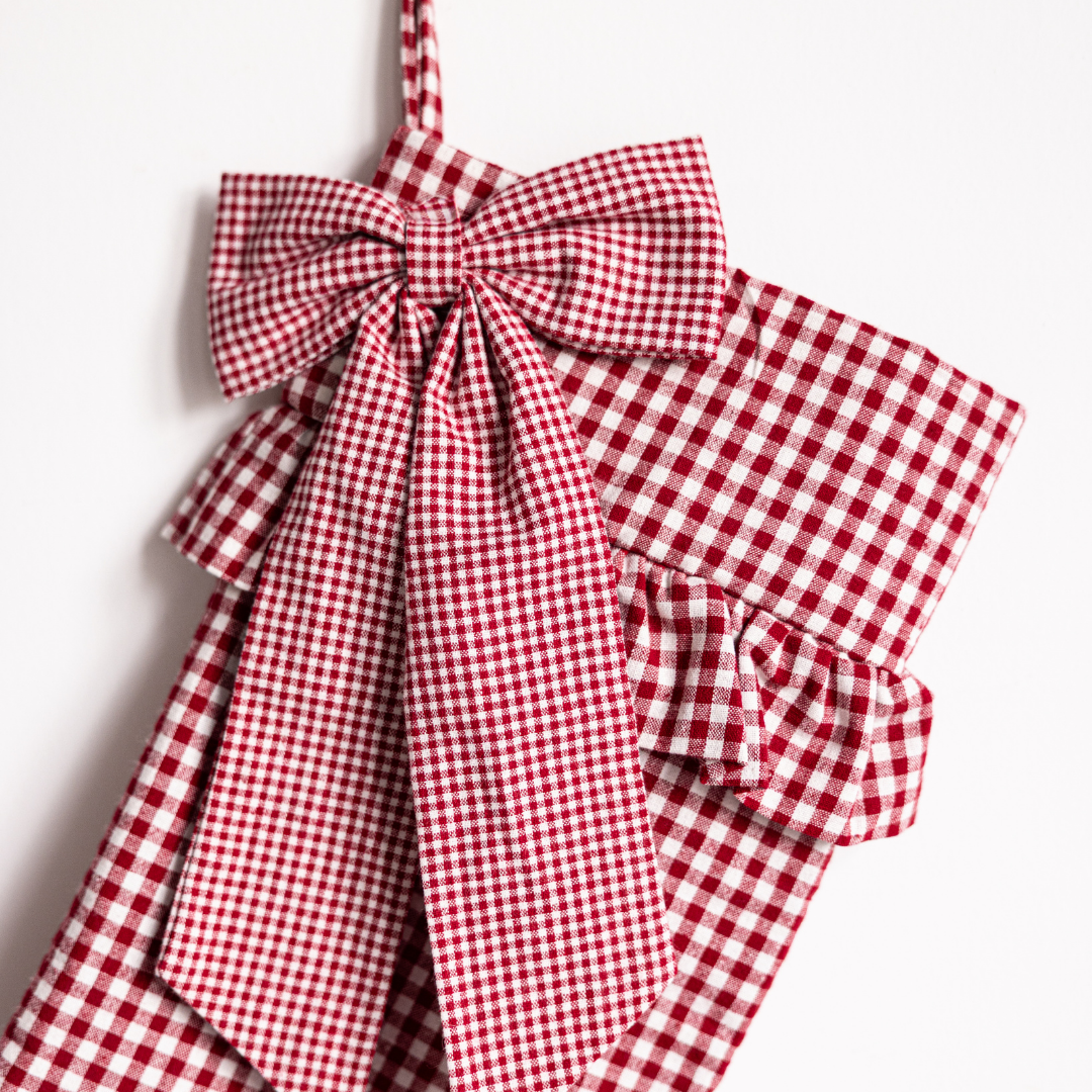 Red gingham bow holiday stocking by Luxe B Co featuring festive red and white checkered pattern and decorative bow detail.