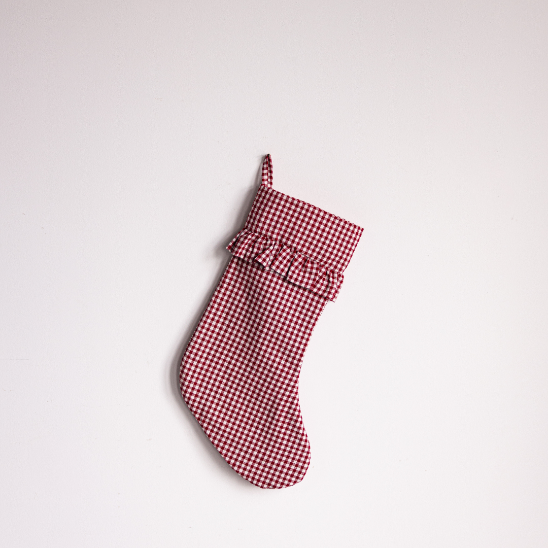 Red gingham holiday stocking by Luxe B Co with festive pattern and plush cuff, perfect for Christmas décor.