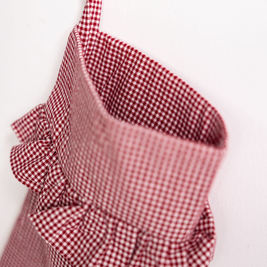 Red mini gingham holiday stocking by Luxe B Co with white cuff and hanging loop, perfect for festive decor.