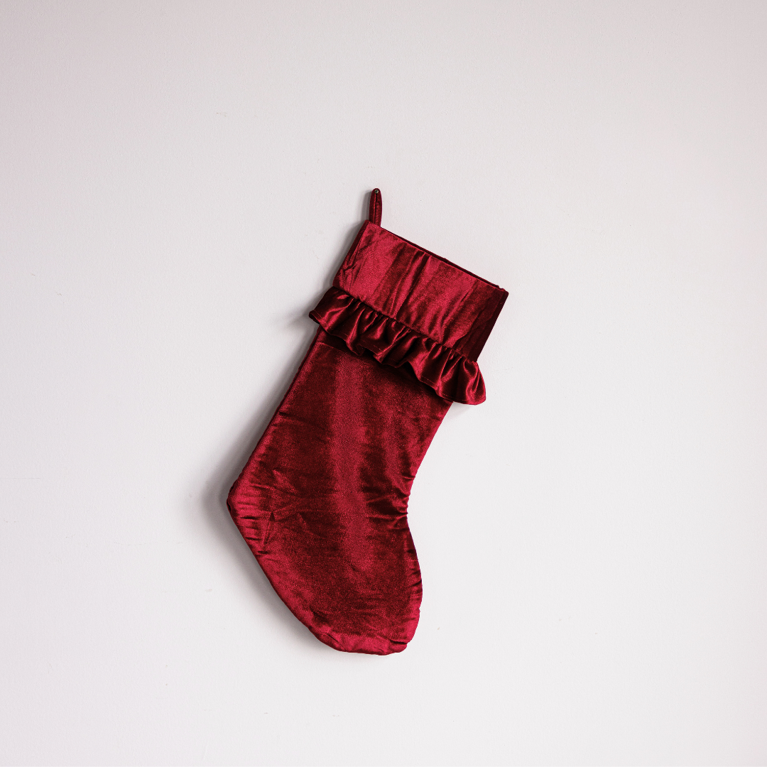 Red velvet holiday stocking by Luxe B Co featuring a festive design, perfect for Christmas decor and gift filling.