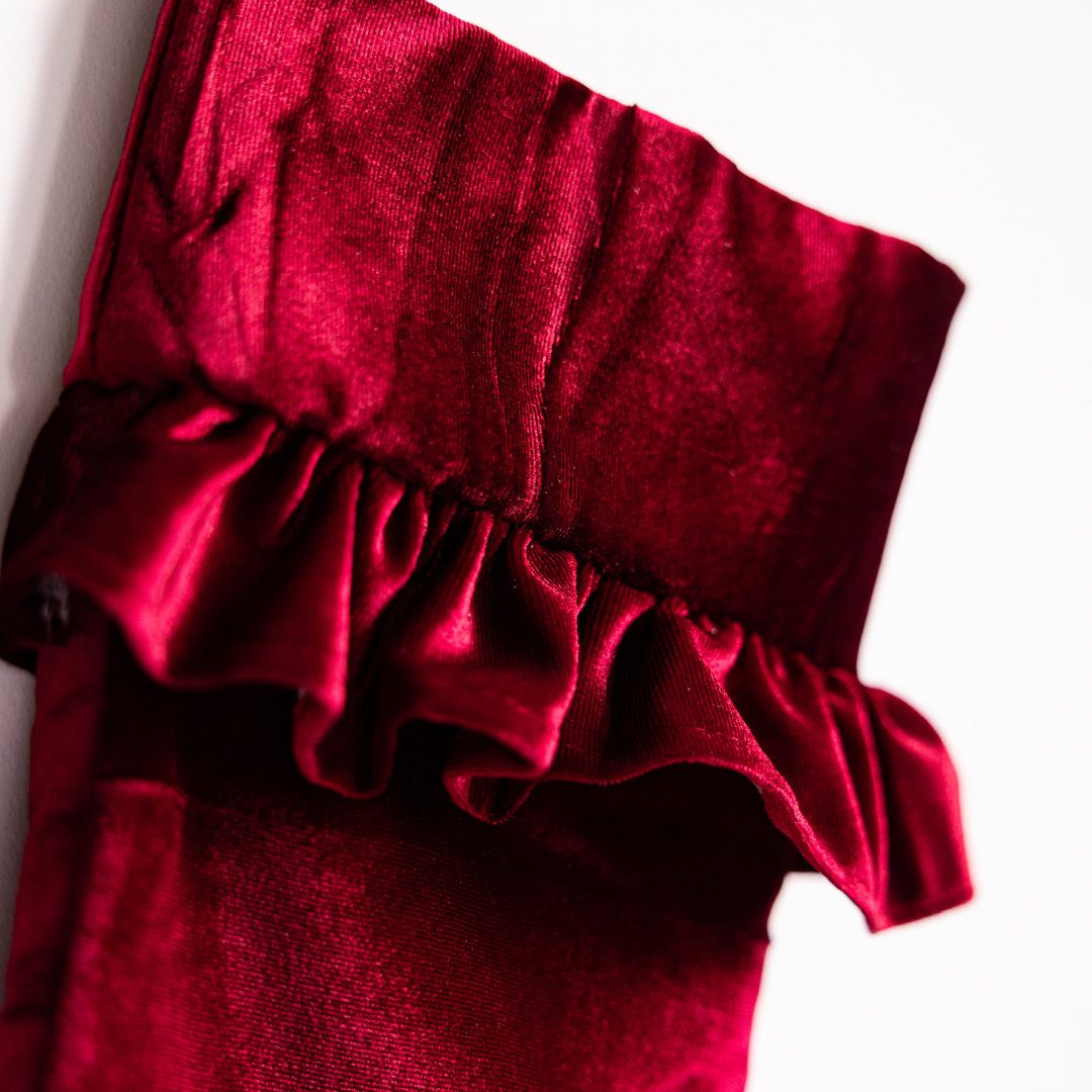 Red velvet holiday stocking by Luxe B Co with white cuff and festive design, perfect for Christmas decor.