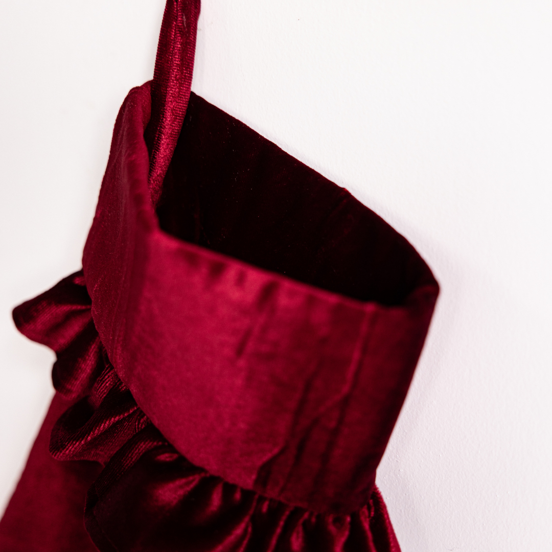 Red velvet holiday stocking by Luxe B Co with festive trim, perfect for Christmas décor and holiday cheer.