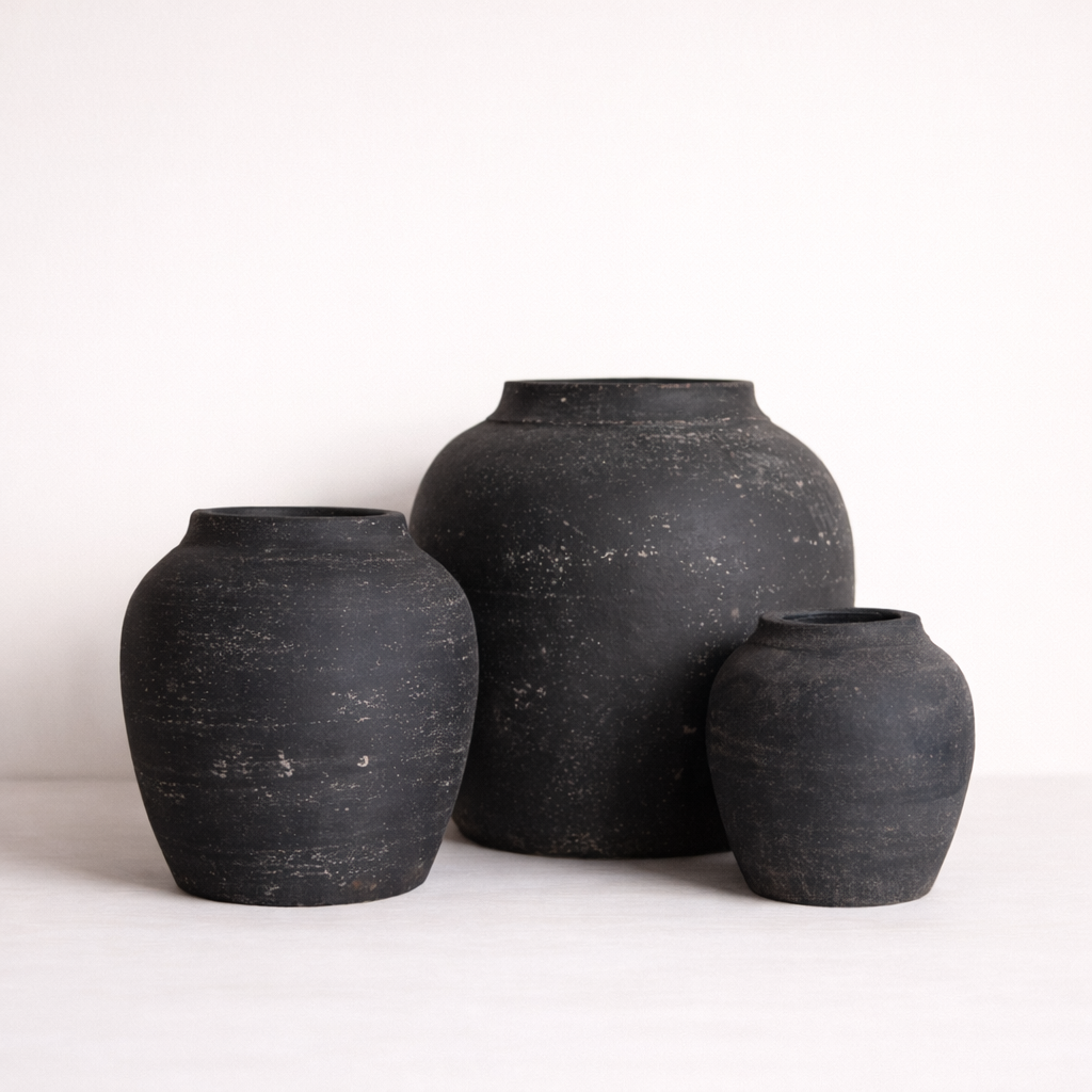 Three black ceramic jars of varying sizes on a white background
