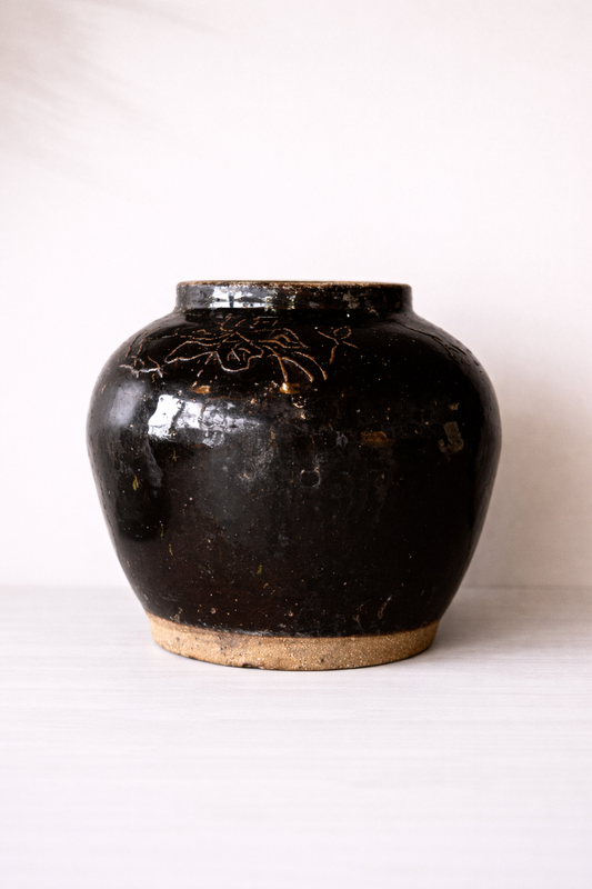 Black ceramic jar with decorative patterns on a white background