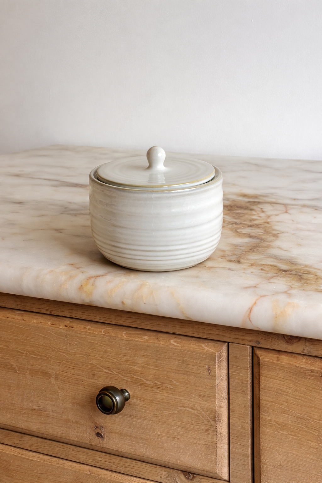 White ceramic jar with lid on a marble countertop